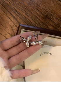 Close-up of elegant silver pearl ear cuff with cubic zirconia on hand-held display