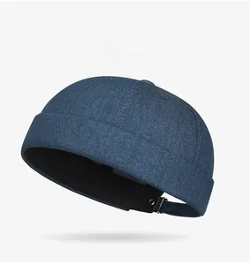 Detail of dark blue denim docker hat featuring adjustable metal strap and twill texture