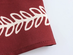 Detail of burgundy ethnic print dress showing leaf pattern and precision stitching