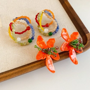 Close-up of vintage glass flower earrings and bead hoops displayed on a wooden tray