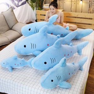 Detailed comparison of five sizes of blue plush shark toys with star embroidery on a bed