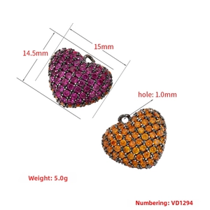 Macro detail of heart shaped charms featuring vibrant pink and orange pave crystals