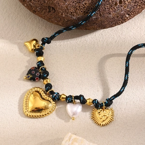 Close-up of woven rope necklace with mixed heart charms in gold finish and pearl