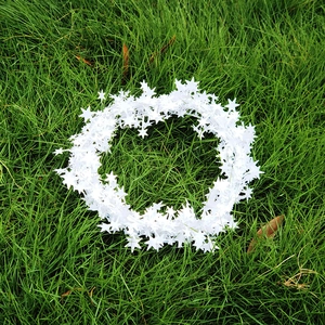 Close-up of white star tinsel garland for Christmas decoration on green grass background