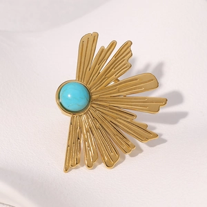 Détail de la broche soleil en or vintage avec centre turquoise et texture radiale