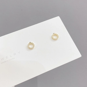 Close-up of gold geometric stud earrings with micro-pave cubic zirconia on a gray card