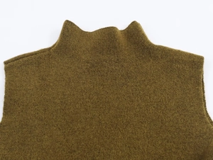 Detail of olive green asymmetric knit top featuring a textured mock neck collar design