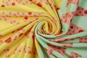 Detailed close-up of printed knit fabric with bright yellow, green, and red polka dots