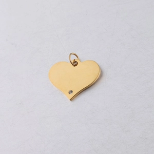 Macro shot of gold heart pendant with embedded diamond on a white background
