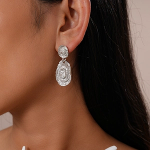 Gros plan de boucles d'oreilles argentées géométriques texturées portées par un mannequin