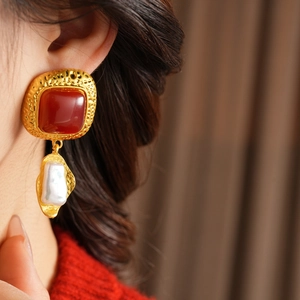 Detail of vintage square gold stud earrings with red gemstone and baroque pearl drop