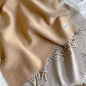 Detail shot of solid color cashmere scarf with tassels and white woven brand label