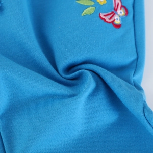 Detailed close-up of vibrant blue knit fabric featuring delicate butterfly embroidery