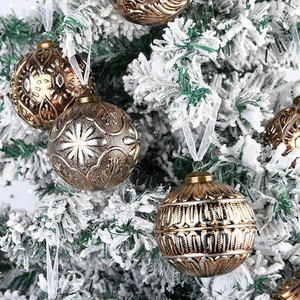 Detailed view of 8cm vintage bronze Christmas balls with embossed patterns on snow tree