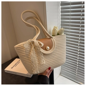 Detail of cream woven tote with brown leather flap, pearl button, and lace bow accent