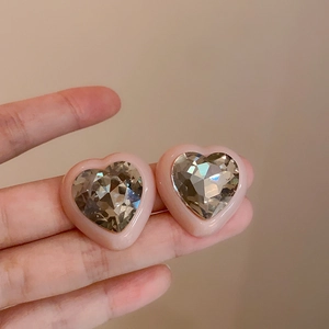 Dettaglio di orecchini a cuore rosa con cristallo brillante tenuti in mano