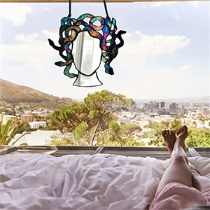 Medusa stained glass suncatcher hanging by a window with scenic outdoor view