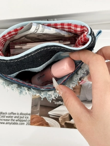 Close-up of denim storage pouch with fringe edges and red checkered lining interior