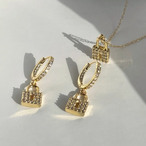 Macro view of 18k gold plated lock pendant earrings and necklace set with sparkling zircon
