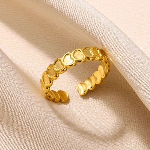 Detailed view of a gold heart-shaped open ring placed on soft beige satin fabric