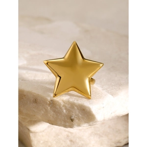 Macro shot of minimalist gold star-shaped ring placed on a white natural stone