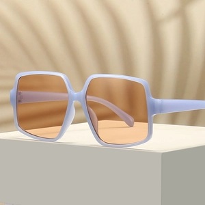 Oversized irregular sunglasses with blue matte frames and orange lenses on a white pedestal