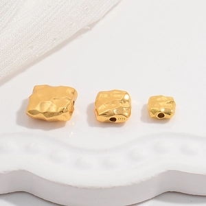 Detailed macro view of S925 stamped square hammered gold spacer beads on lace