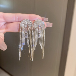 Détail de boucles d'oreilles pendantes argentées avec zircons et franges brillantes