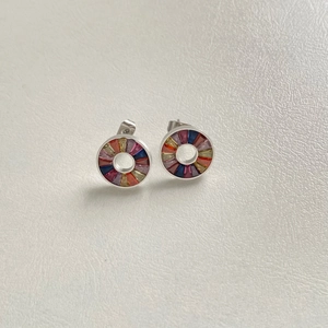 Macro detail of silver stud earrings with vibrant rainbow baguette-cut crystals