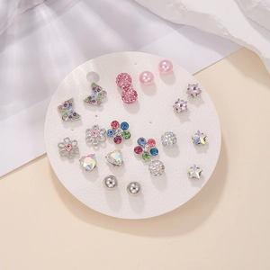 Close-up of set with multiple earrings in flower and heart shapes on white card