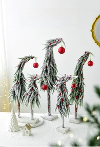 Close-up of snow-flocked mini Christmas trees with red ornaments and square bases