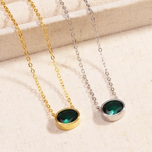 Detailed view of gold and silver emerald pendant necklaces on soft beige fabric