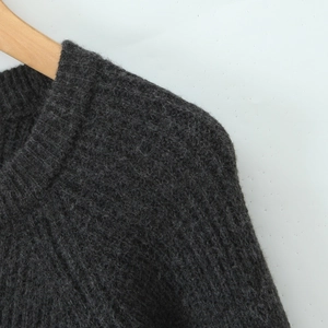 Close-up of dark grey knitted sweater texture and neckline on a wooden hanger