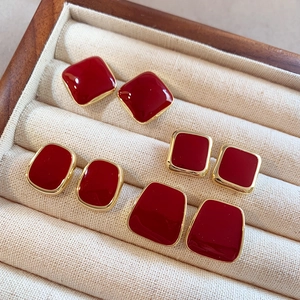 Detailed set of four red enamel geometric gold earrings displayed on beige velvet tray