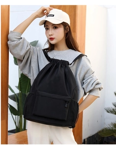Close-up detail of black drawstring backpack, lightweight design, convenient outer pocket.