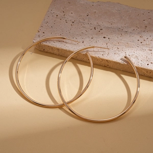 Minimalist gold round hoop earrings resting on a decorative stone with soft lighting