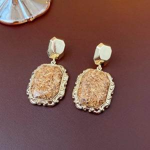 Close-up of vintage golden earrings with brown foil texture in octagonal frames