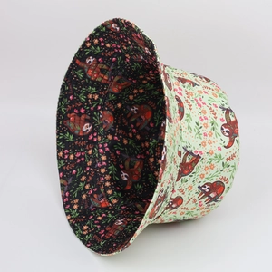 Detail view of double-sided bucket hat featuring cute sloth prints on green and black