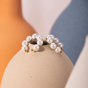 Elegant 18k gold stainless steel hoop earrings with pearls displayed on a beige clay vase