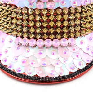 Détail macro de paillettes roses avec clous dorés et décorations en strass rose