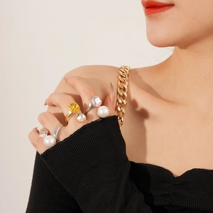 Detailed view of layered rings featuring pearls, square gems, and gold finish