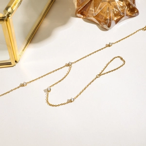 Detail of a gold-plated chain with five sparkling zircons on a white aesthetic background