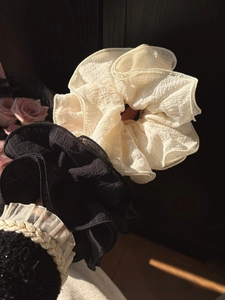 Detailed close-up of layered pleated scrunchies in cream and black with textured fabric