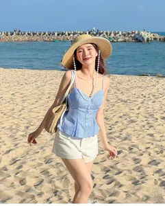 Detail of blue and white striped camisole top with decorative buttons on a summer beach