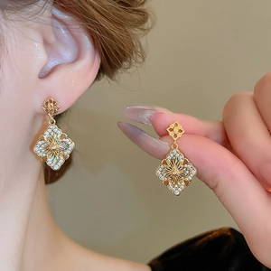 Détail des boucles d'oreilles fleurs plaquées or avec zircone et design géométrique rétro