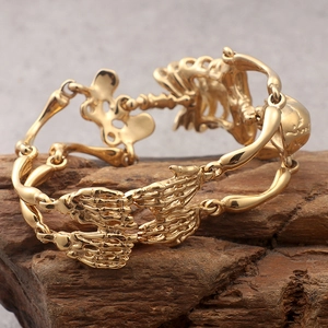 Detail of gothic gold skeleton bracelet with skull bone links on a dark wood background
