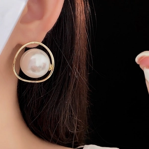 Orecchini a cerchio dorati con perle di alta qualità indossati da una modella elegante