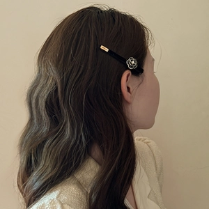 French vintage camellia hair clip with black velvet finish on female model side view