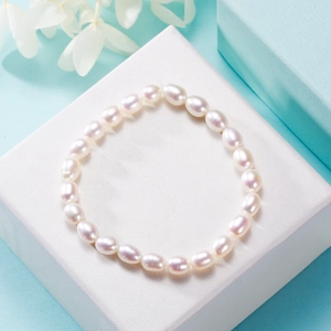 Detail of white oval freshwater pearl elastic bracelet on a textured white gift box