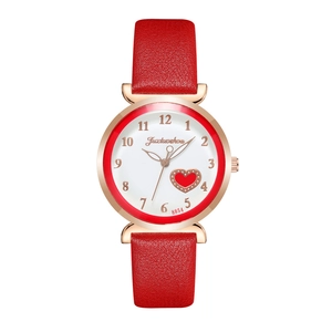 Close-up of a women's watch featuring a red heart motif on a white dial with gold accents